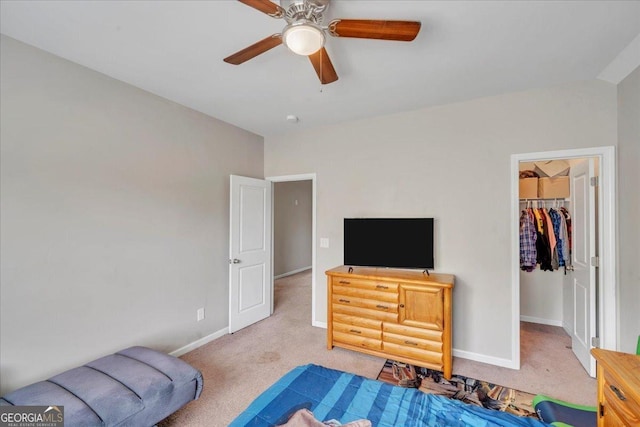 carpeted bedroom featuring a closet, baseboards, a ceiling fan, and a walk in closet