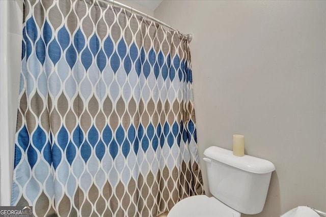 bathroom with toilet and curtained shower