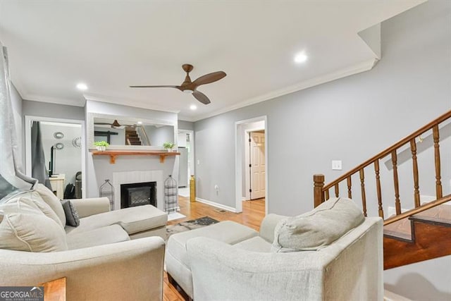 living room with light wood-style flooring, ceiling fan, and ornamental molding