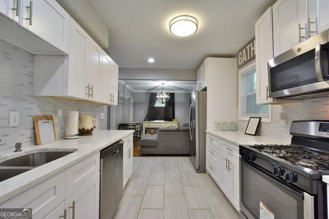 kitchen featuring decorative backsplash, white cabinets, stainless steel appliances, and plenty of natural light