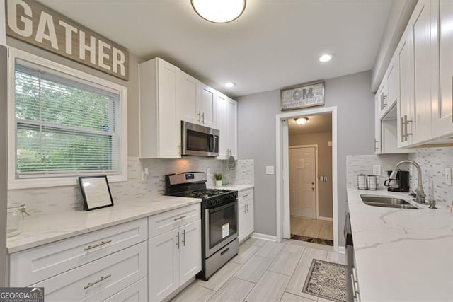 kitchen with white cabinetry, tasteful backsplash, appliances with stainless steel finishes, and a sink