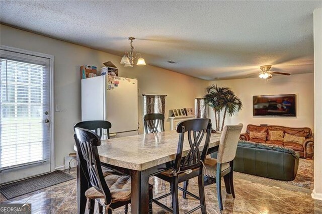 dining space with a textured ceiling and ceiling fan with notable chandelier