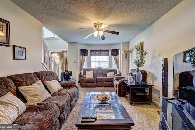 living area featuring stairway, ceiling fan, a textured ceiling, and light carpet
