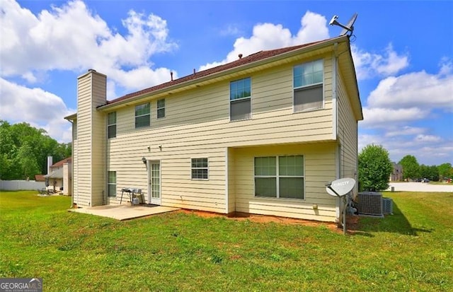 back of property featuring a patio, central air condition unit, a lawn, and a chimney