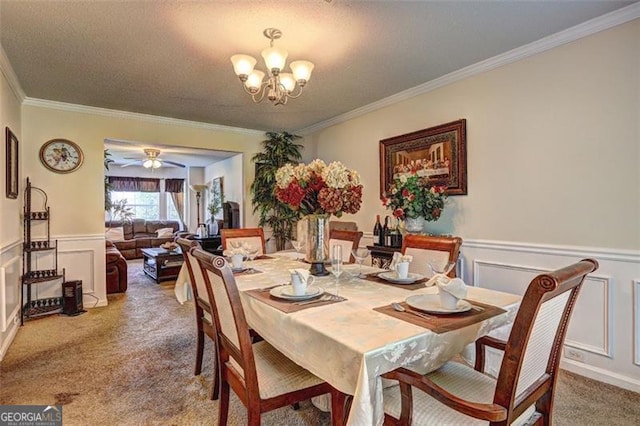 dining space with a decorative wall, ornamental molding, wainscoting, carpet floors, and ceiling fan with notable chandelier