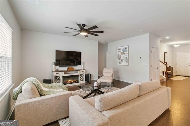 340 Paulownia Cir, Mcdonough, GA 30253 - living area with stairway, ceiling fan, baseboards, a glass covered fireplace, and dark wood-type flooring
