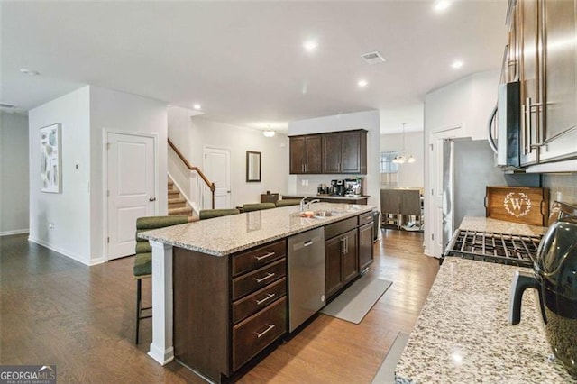 340 Paulownia Cir, Mcdonough, GA 30253 - kitchen with dark wood finished floors, stainless steel appliances, dark brown cabinets, and a kitchen breakfast bar