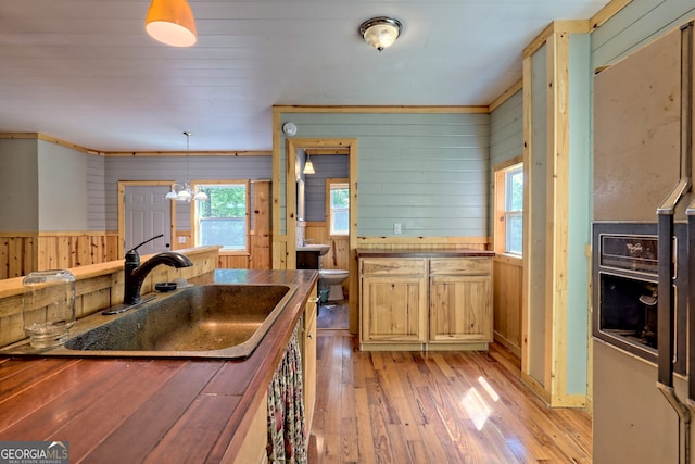 266 Ritchie Rd, Tiger, GA 30576 - kitchen featuring hanging light fixtures, a sink, wood walls, and light wood-type flooring
