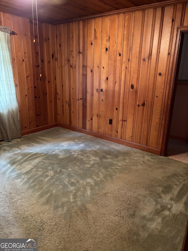 interior space featuring carpet flooring, wooden ceiling, wood walls, and baseboards