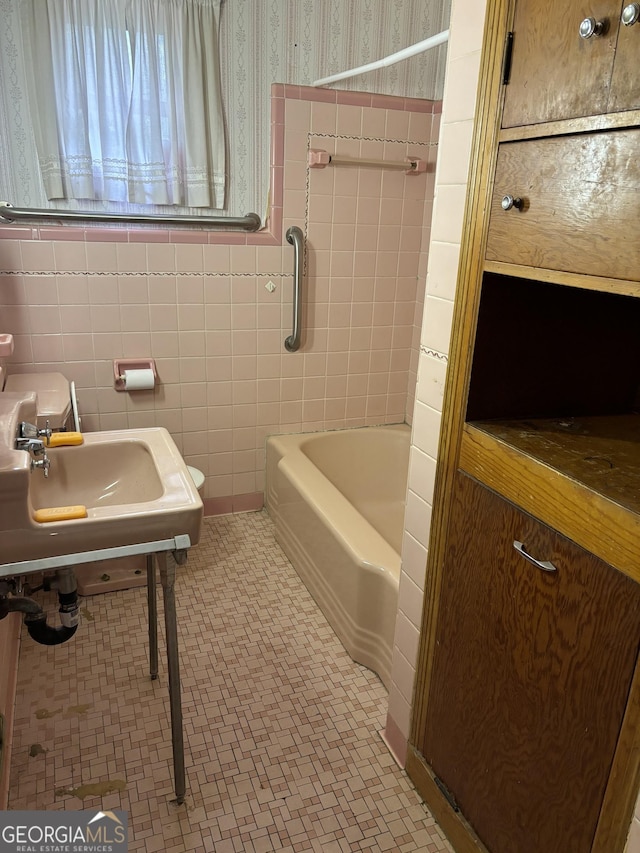 full bath with tile patterned floors, a sink, and tile walls