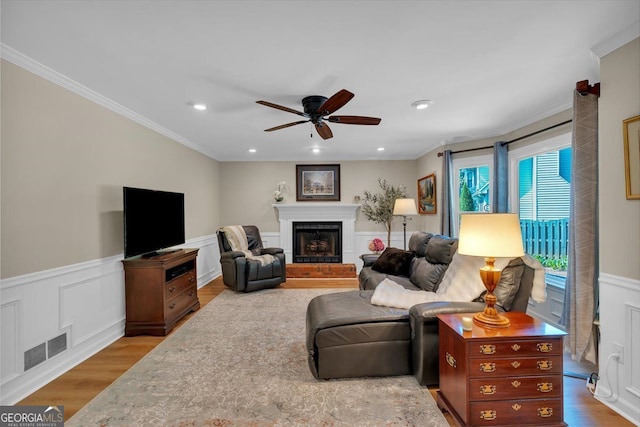 living room with ceiling fan, ornamental molding, wood finished floors, and visible vents