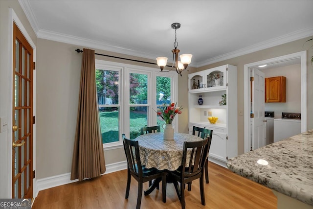 dining area featuring crown molding, a notable chandelier, washing machine and dryer, and light wood-style floors