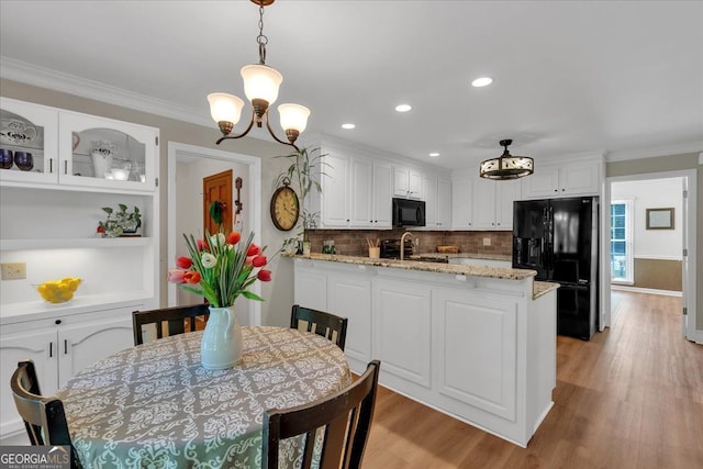 kitchen with crown molding, a peninsula, light wood-type flooring, white cabinets, and black appliances