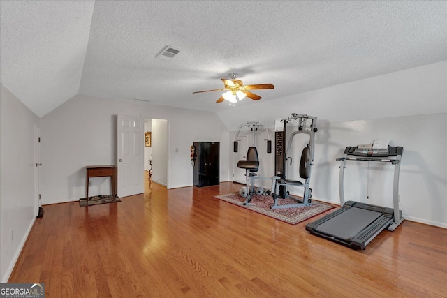 workout area featuring ceiling fan, lofted ceiling, wood finished floors, and visible vents