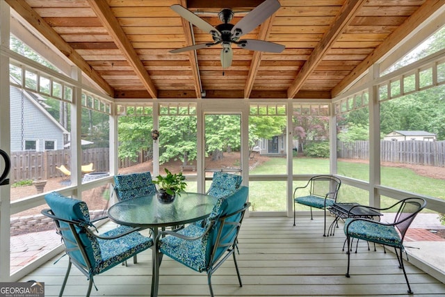 sunroom / solarium featuring outdoor dining area, a ceiling fan, and beam ceiling