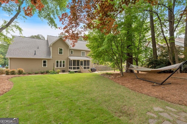 back of property with a lawn, a shingled roof, and a sunroom