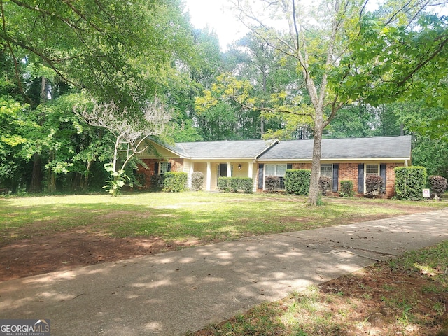 ranch-style house featuring concrete driveway, brick siding, and a front lawn