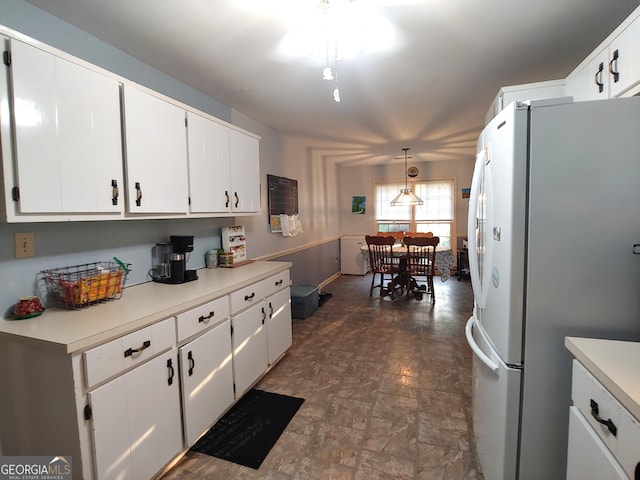 kitchen featuring decorative light fixtures, white cabinetry, light countertops, and freestanding refrigerator