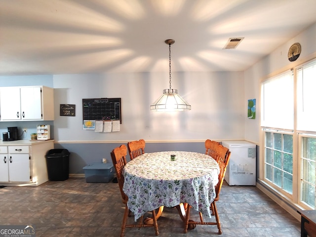 dining room featuring stone finish flooring, visible vents, and baseboards