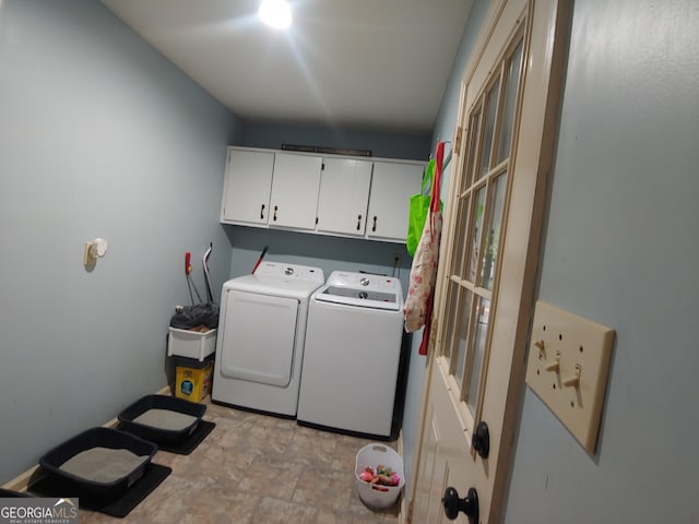 laundry room featuring stone finish floor, washing machine and clothes dryer, and cabinet space