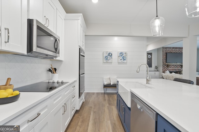 kitchen with white cabinetry, decorative backsplash, blue cabinets, light countertops, and black appliances