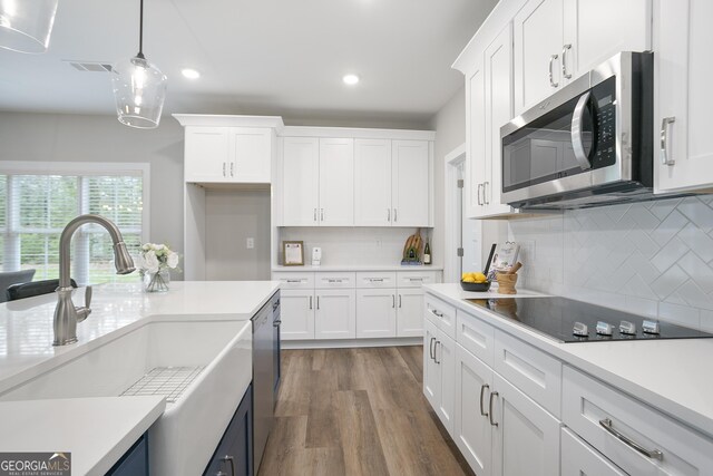 kitchen featuring recessed lighting, a sink, stainless steel appliances, white cabinetry, and light countertops