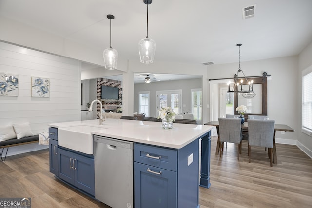 kitchen with blue cabinets, dishwasher, a sink, visible vents, and open floor plan