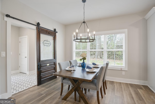 dining area featuring an inviting chandelier, wood finished floors, a barn door, and baseboards