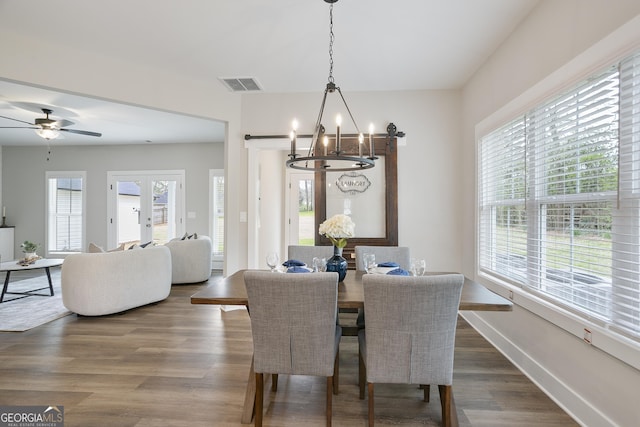 dining room featuring dark wood-type flooring, visible vents, baseboards, french doors, and ceiling fan with notable chandelier