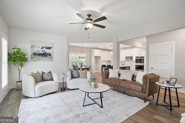 living area featuring dark wood-type flooring, a ceiling fan, and baseboards