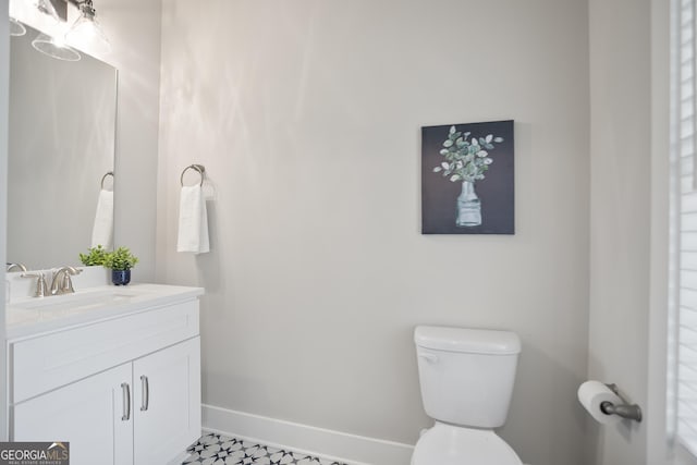 bathroom with vanity, toilet, and baseboards