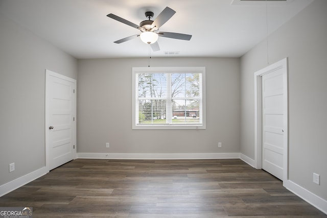 spare room with attic access, ceiling fan, baseboards, visible vents, and dark wood-type flooring
