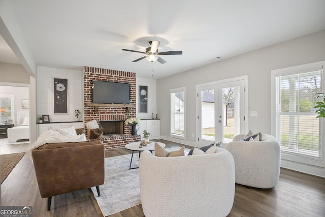 living room featuring wood finished floors, a ceiling fan, and a brick fireplace