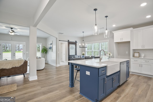 kitchen with recessed lighting, a barn door, a sink, white cabinetry, and open floor plan