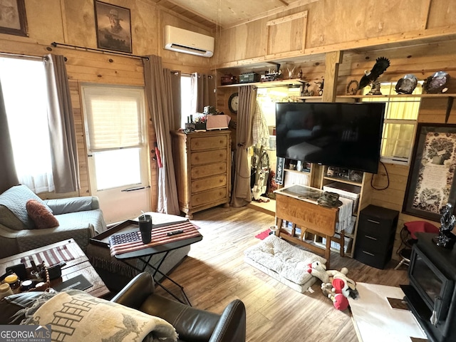 living area featuring wooden walls, a wood stove, a wall mounted AC, and wood finished floors