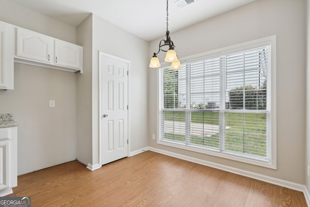 unfurnished dining area with light wood finished floors, baseboards, and a chandelier