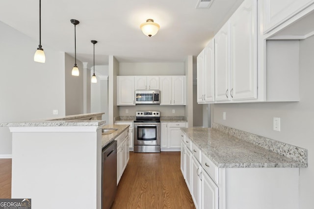 kitchen with stainless steel appliances, dark wood-style flooring, white cabinetry, and decorative light fixtures