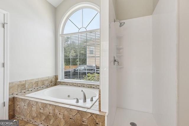 full bath with healthy amount of natural light, a stall shower, and a jetted tub