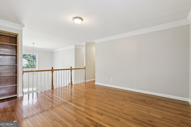 empty room with hardwood / wood-style floors, ornamental molding, and baseboards