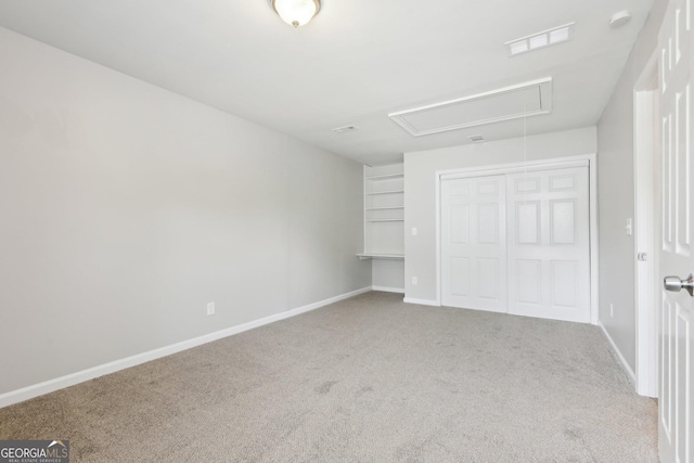 unfurnished bedroom featuring attic access, carpet floors, a closet, and baseboards