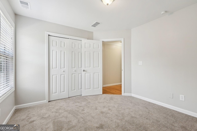 unfurnished bedroom with multiple windows, carpet flooring, a closet, and baseboards