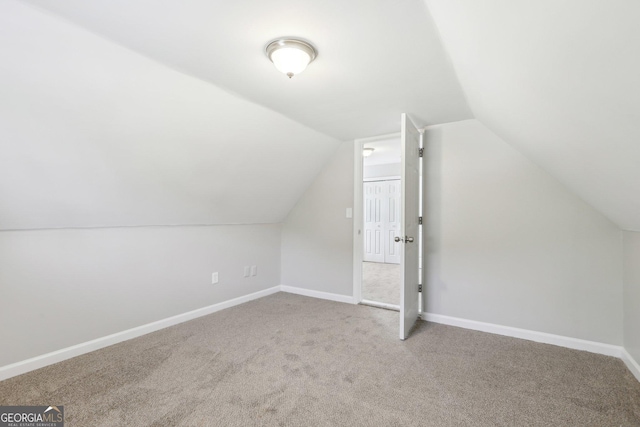 additional living space with carpet flooring, vaulted ceiling, and baseboards