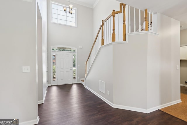 entrance foyer with stairway, a chandelier, wood finished floors, baseboards, and a towering ceiling