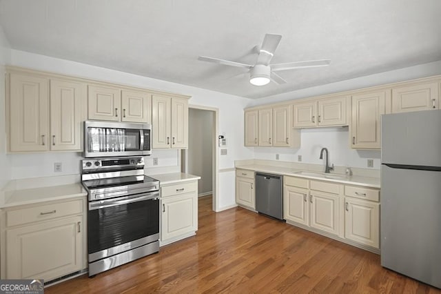 kitchen with cream cabinets, a sink, stainless steel appliances, and light countertops