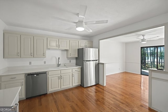 kitchen featuring a sink, ceiling fan, light countertops, appliances with stainless steel finishes, and wood finished floors