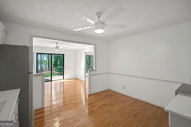 unfurnished dining area with light wood-type flooring and ceiling fan