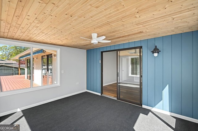interior space with baseboards, dark carpet, a ceiling fan, and wood ceiling