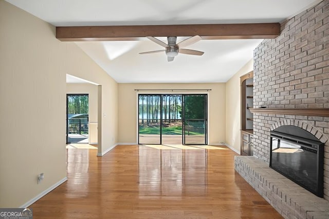 unfurnished living room with ceiling fan, baseboards, a brick fireplace, wood finished floors, and vaulted ceiling with beams