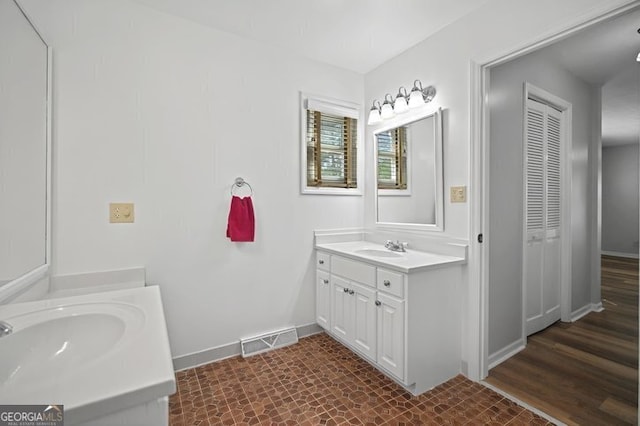 full bathroom featuring baseboards, visible vents, two vanities, and a sink