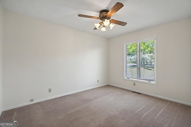 carpeted empty room featuring visible vents, a ceiling fan, and baseboards